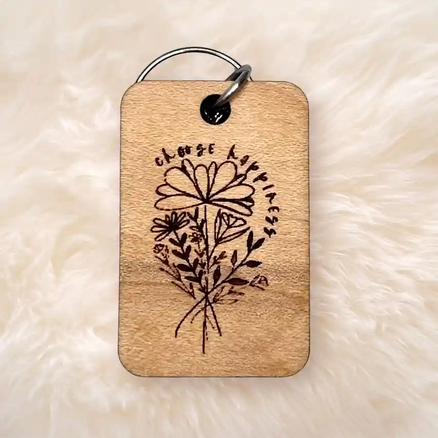 Wood keychain on fur background with flowers and the words choose happiness on the front.