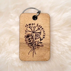 Wooden keychain with engraved floral design and  choose happiness on a soft beige background