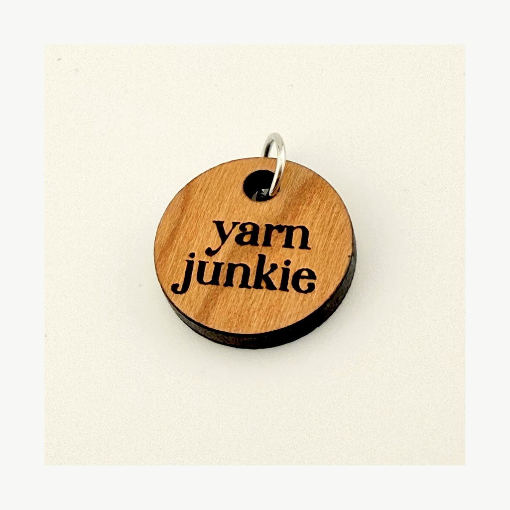 Wooden keychain with 'yarn junkie' text on a beige background