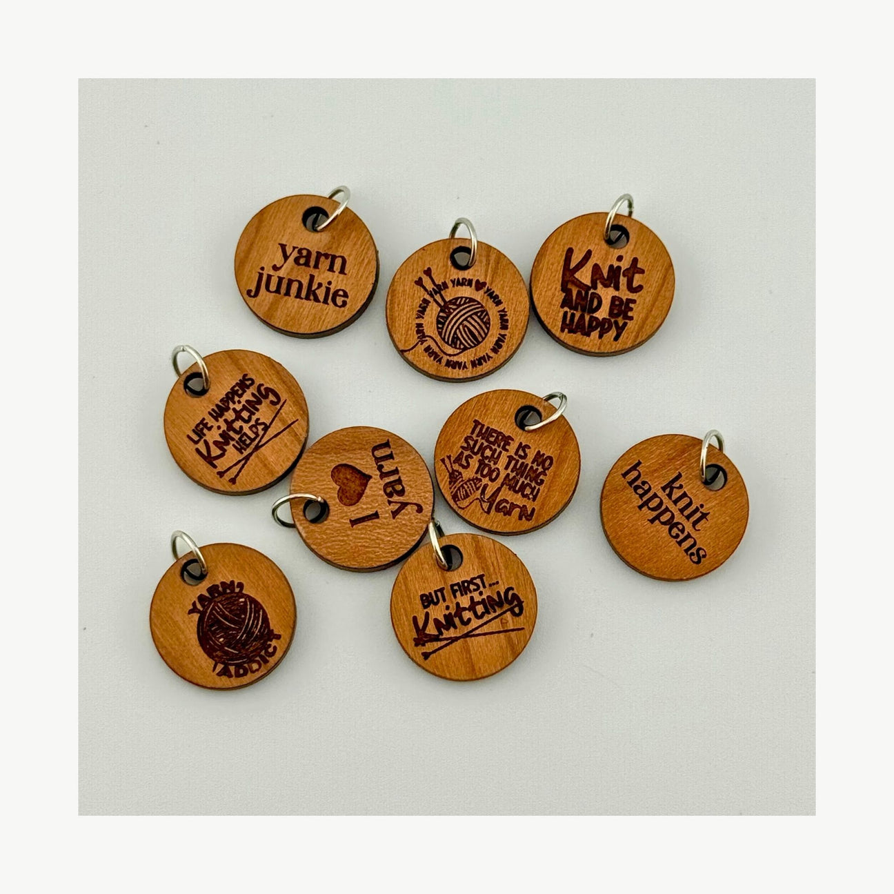 Set of wooden stitch markers with engraved text on a light gray background