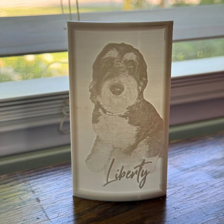 Lithophane with a dog illustration and 'Liberty' text on a wooden surface with a window in the background