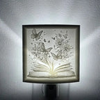 lithophane nightlight with an open book with butterflies and flowers on a white wall