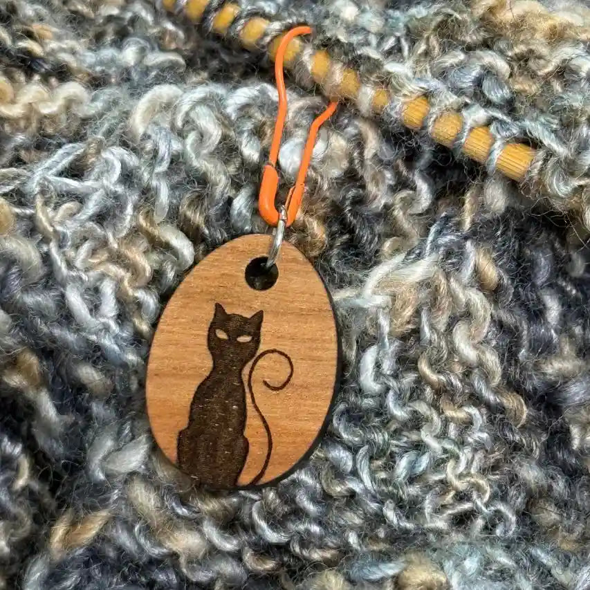 Wooden pendant with cat design on a textured fabric background