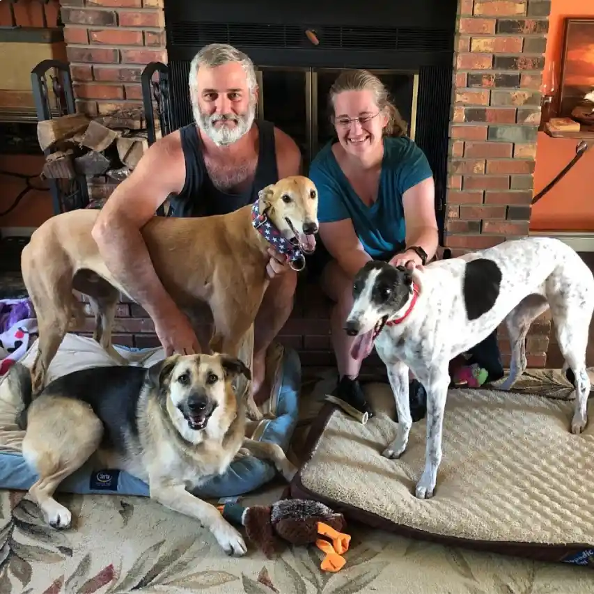 Two people with three dogs in a living room setting.
