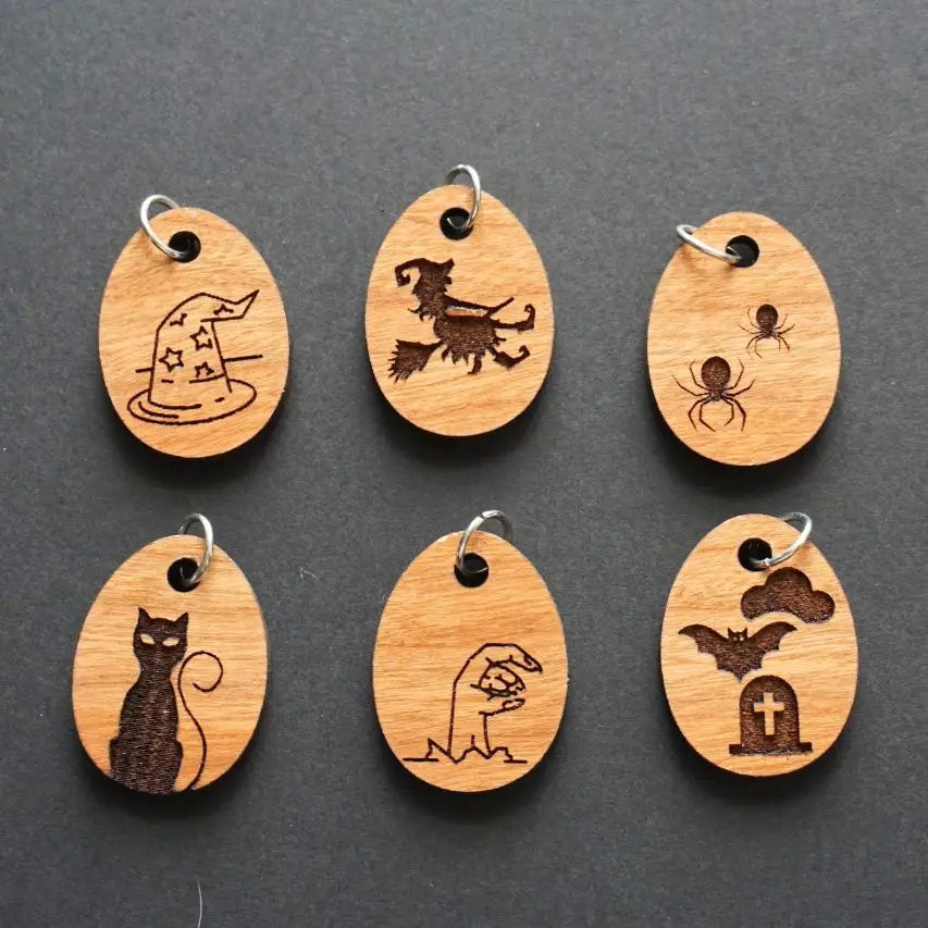 Set of six wooden charms with Halloween-themed designs on a dark gray background.
