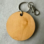 Wooden keychain with metal clip on a gray background