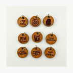 Set of wooden charms with knitting-themed phrases on a white background