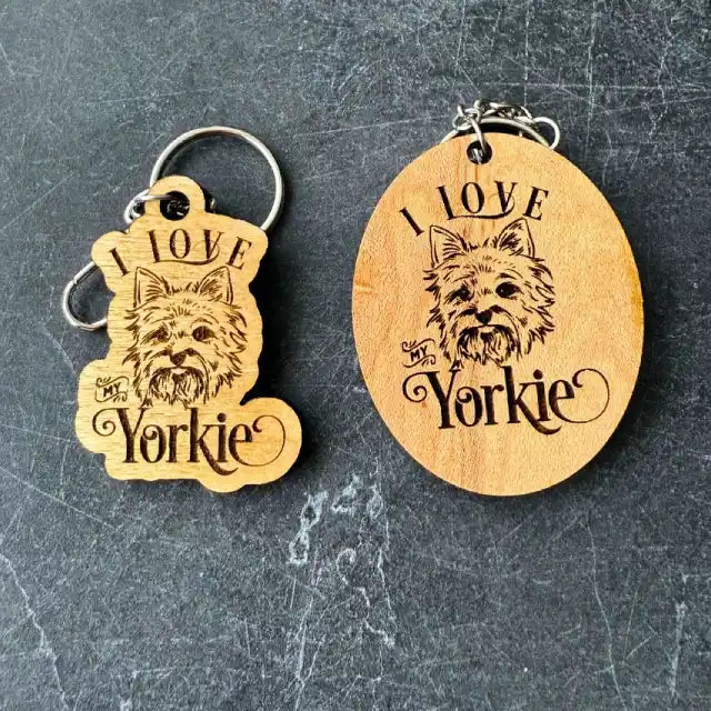 Two wooden keychains with 'I Love Yorkie' text and dog illustration on a dark textured surface.