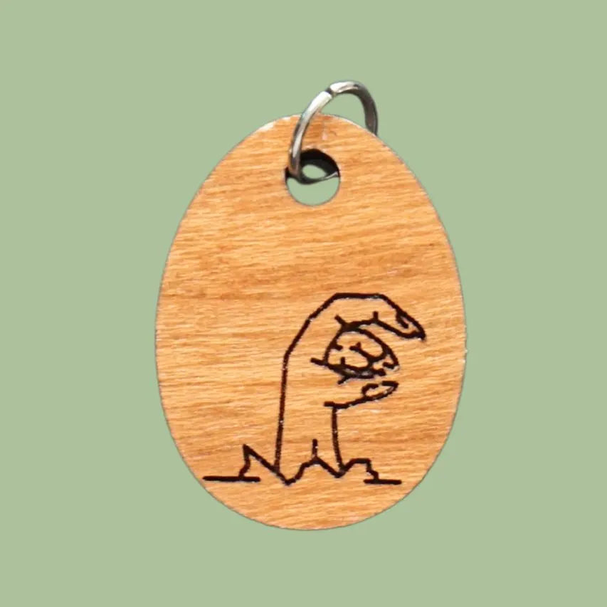 Wooden pendant with engraved mummy hand design on a green background