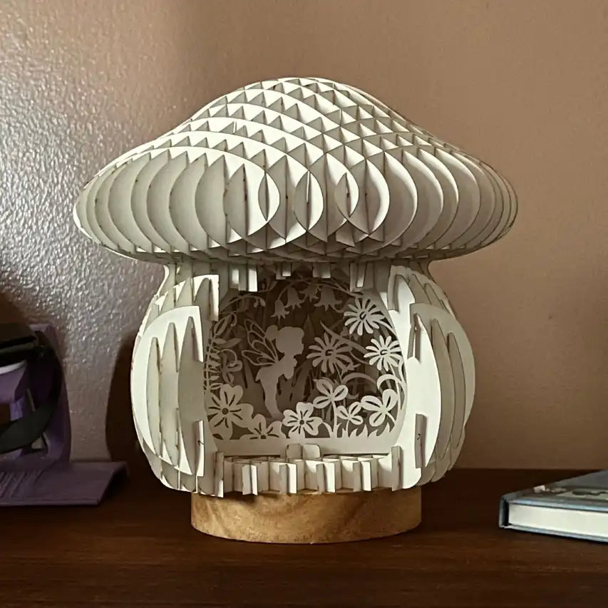 Unlit mushroom-shaped decorative lamp with cut-out designs on a wooden base against a beige wall.