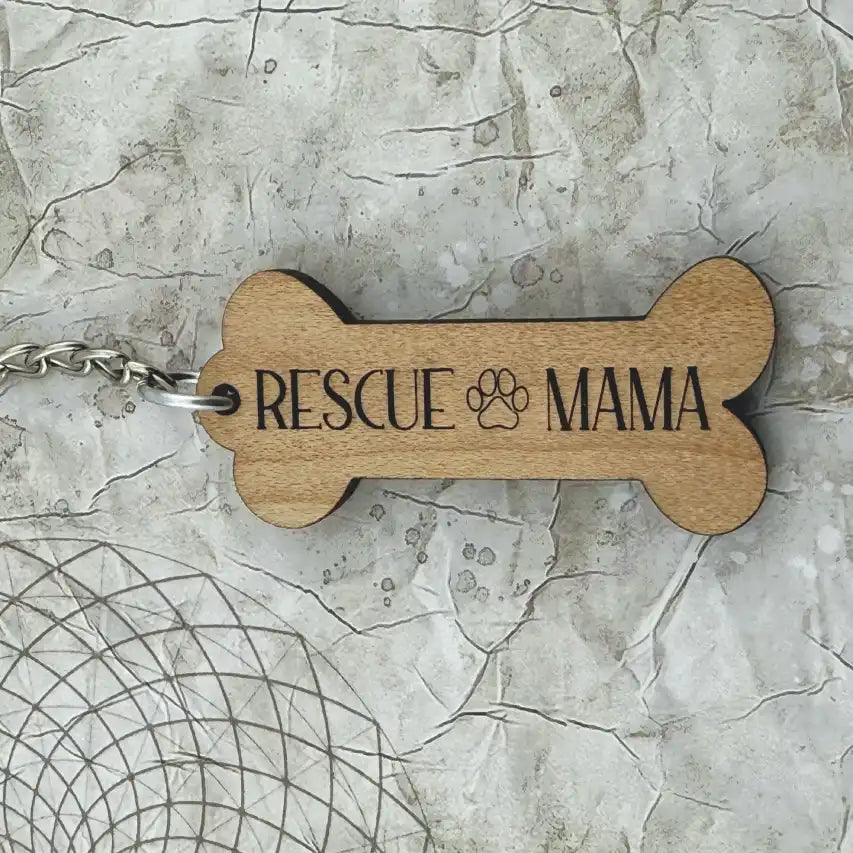 Wooden bone-shaped keychain with 'Rescue Mama' text on a textured surface